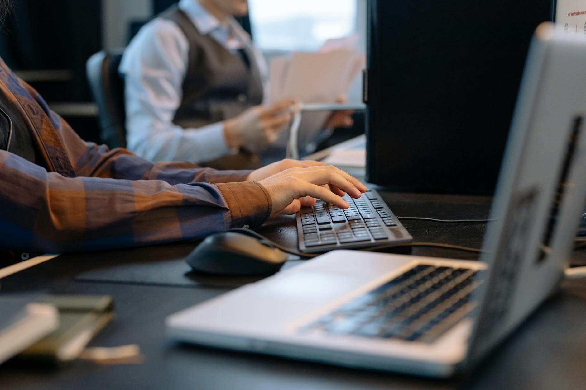 men sitting at the desks in an office and using computers